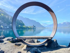 Circular lakeside sculpture framing Lake Geneva with Alpine mountains near Montreux and Chillon Castle