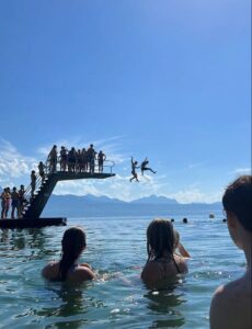 People swimming and jumping into Lake Geneva from a diving platform on a sunny summer day